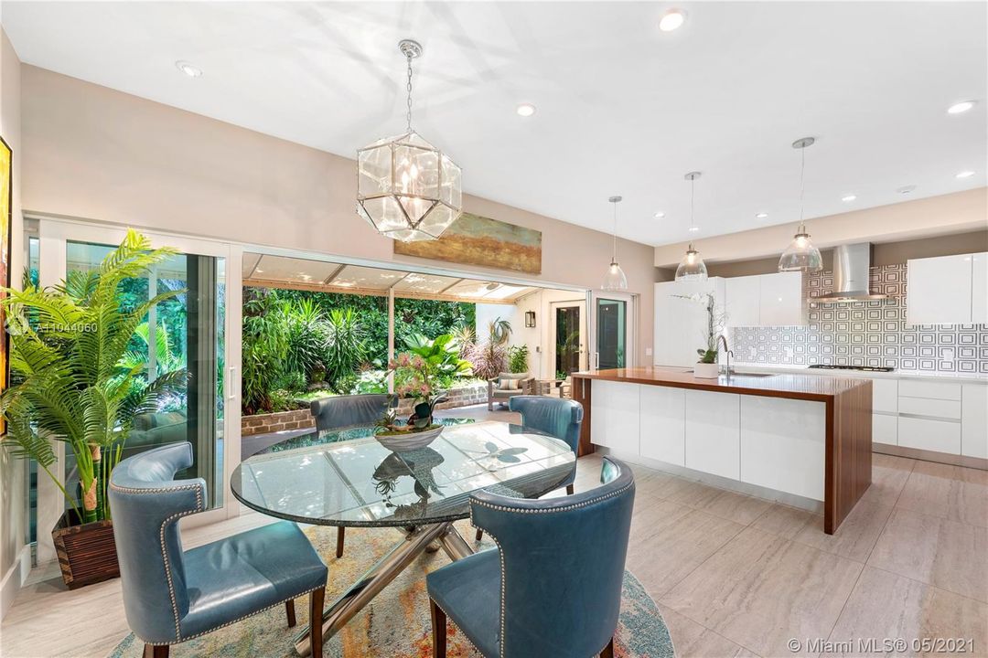 Ultra-modern eat-in kitchen with wall of sliding glass doors opening to views of the lushly landscaped back yard and meditation garden