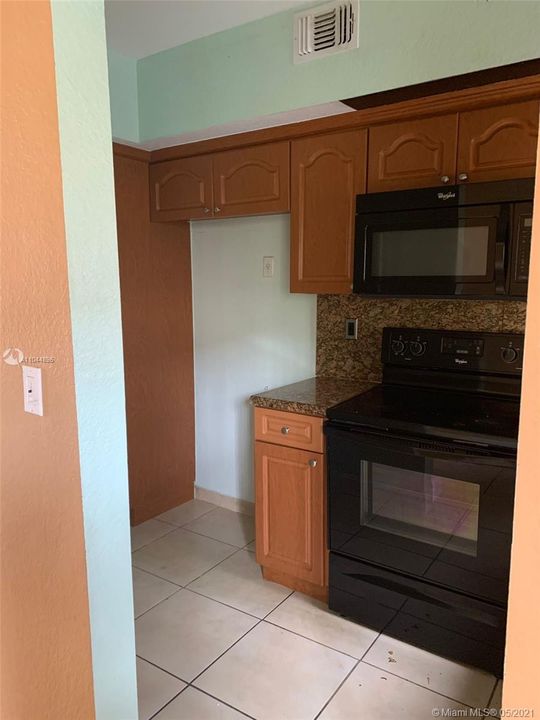 Kitchen missing the fridge but with matching whirlpool microwave and stove.