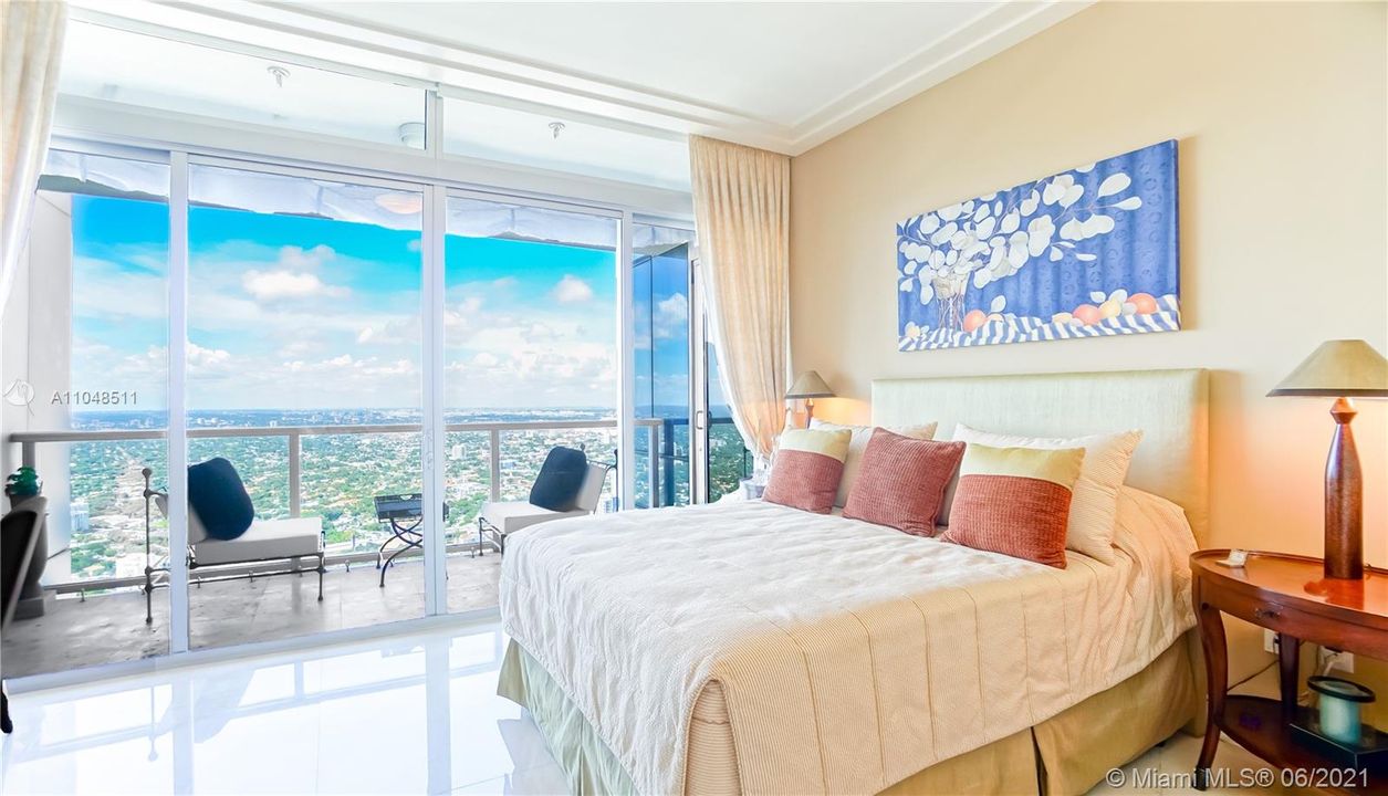 Spacious guest bedroom with panoramic city views and terrace access