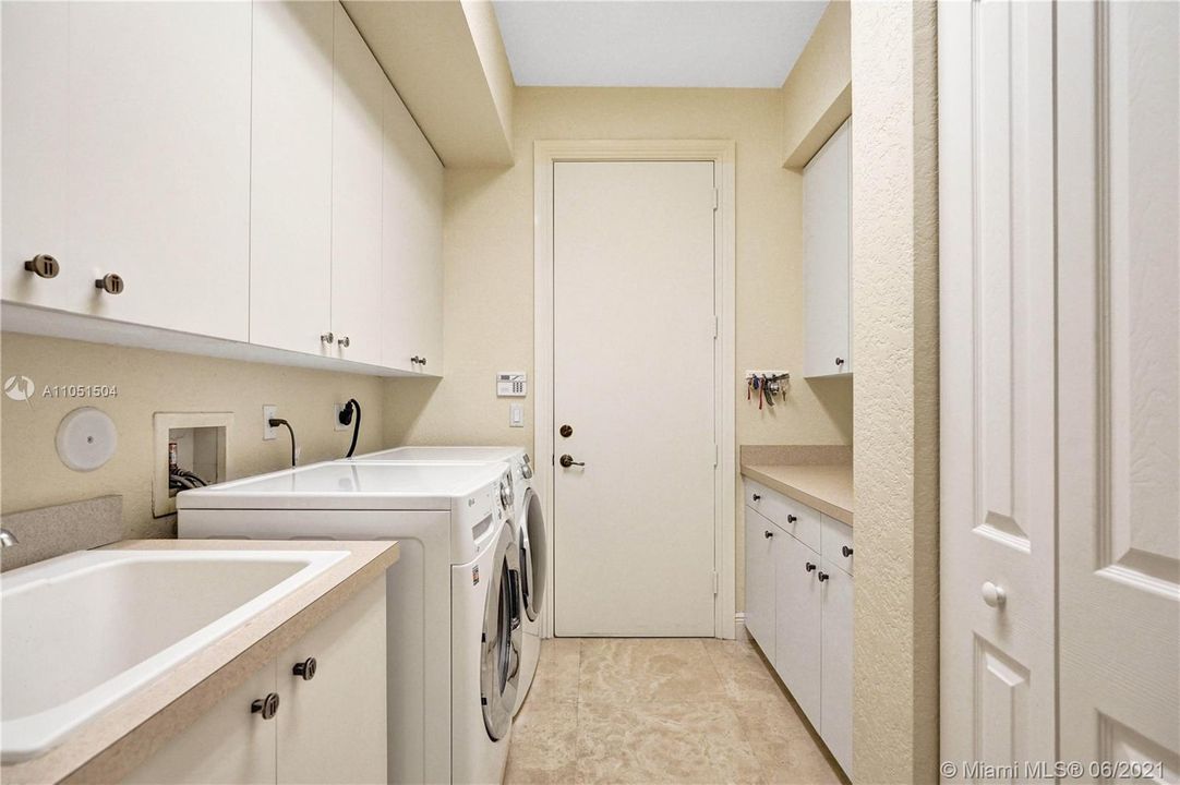 Spacious laundry room with custom made cabinets throughout and access to the garage