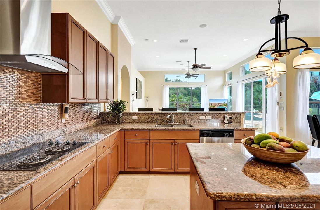 Gourmet kitchen with wood cabinets and matching granite countertops and glass mosaic back splash