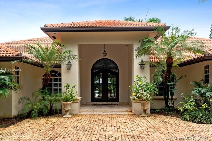 Grand entrance to home with lush tropical landscaping.