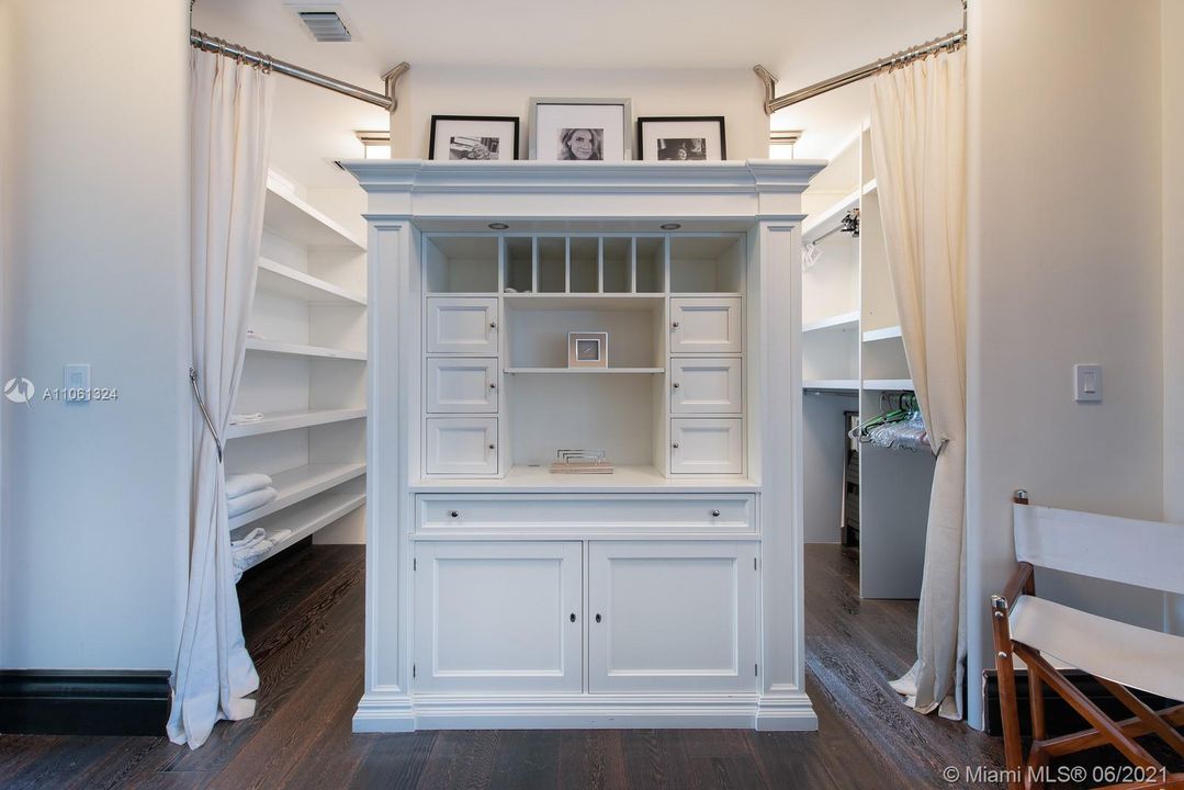 Spacious wrap around walk-in closet with nice drapery to give it a different, elegant touch.