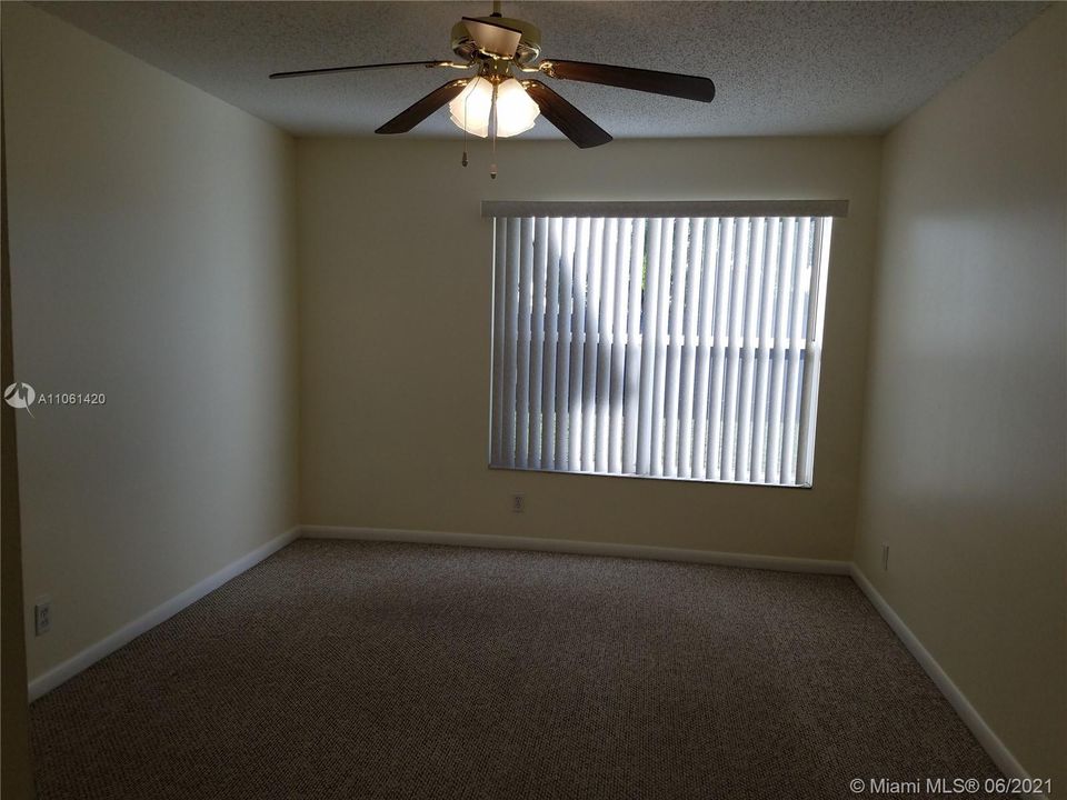 Master bedroom is carpeted and has a paddle fan.