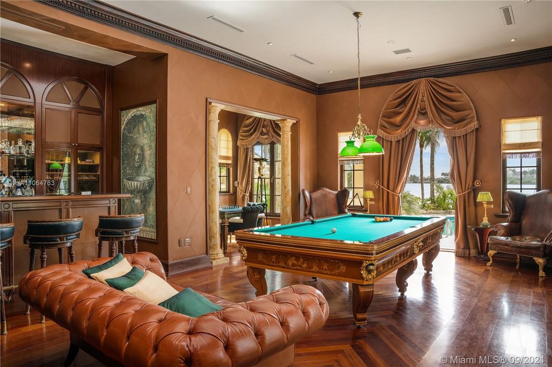 Billiards room with bar area, cigar area, fireplace next to movie theatre room