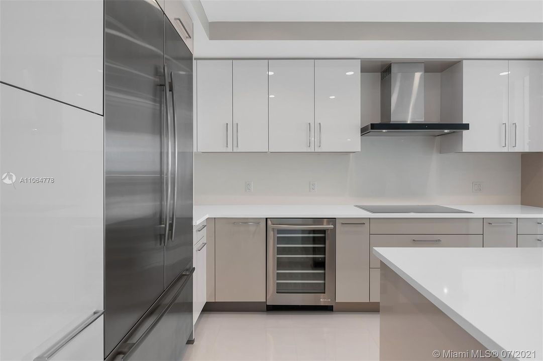 Jennair appliances, Icemaker, Pantry, wine fridge, pullout trash, Wall oven and microwave, Sleek taupe and white European cabinets and quartz countertops