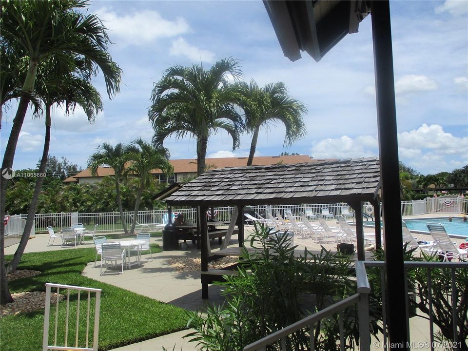 Two shaded huts with picnic tables by pool