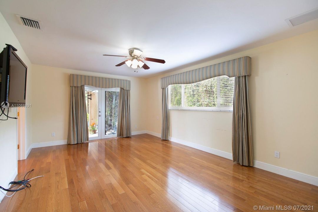Large main bedroom with wood flooring and French doors with access to the backyard & patio.