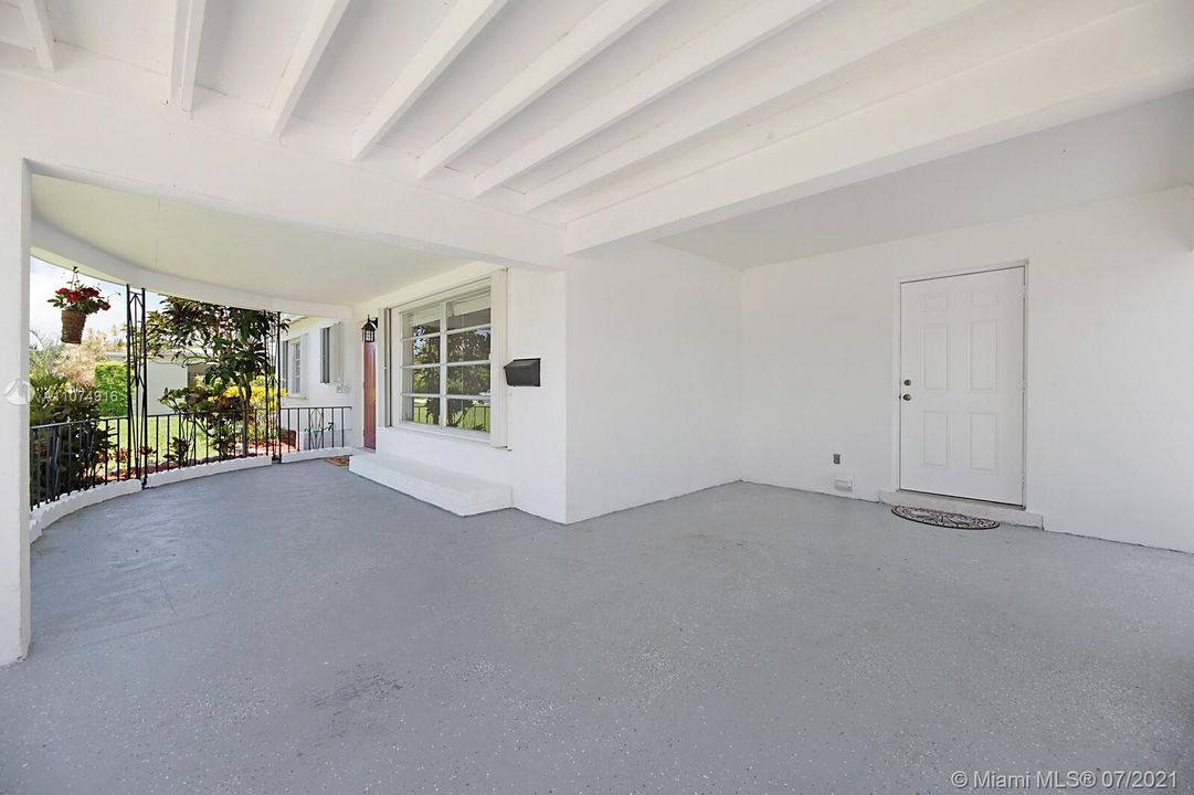 Covered front porch & carport with pedestrian door.