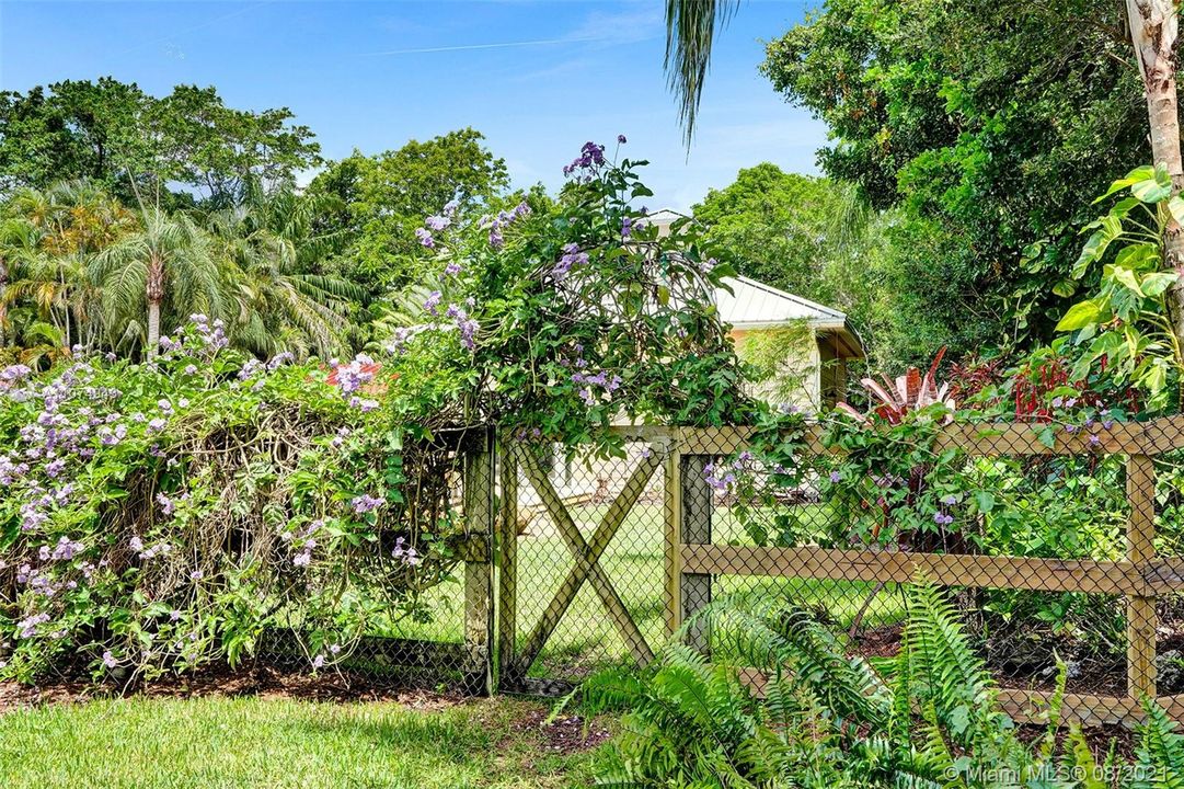 Charming garden gate leading to lushly landscaped backyard.