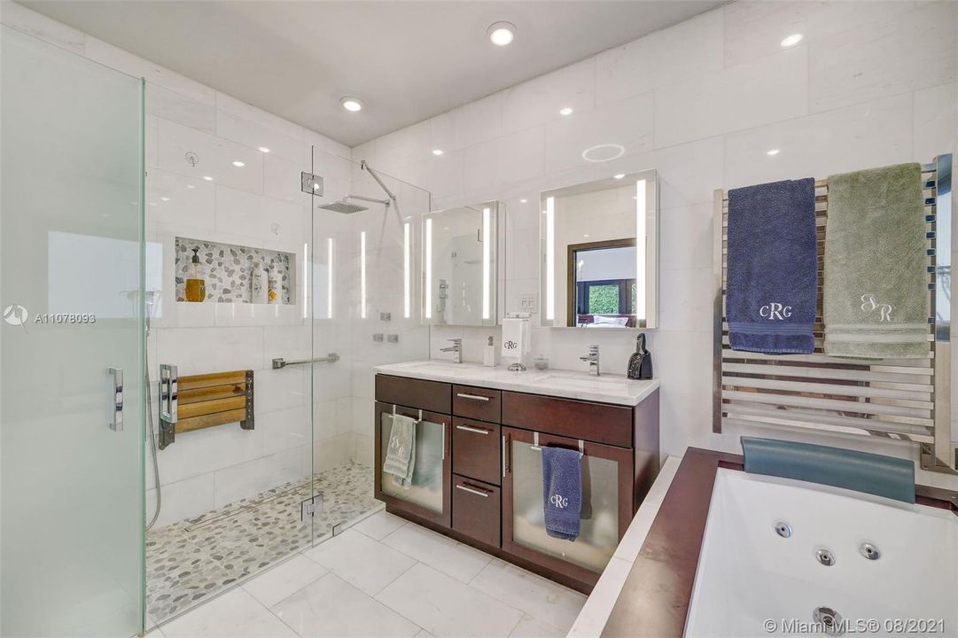 Primary bathroom glass shower enclosure, rain-shower design, and jacuzzi soaking tub.