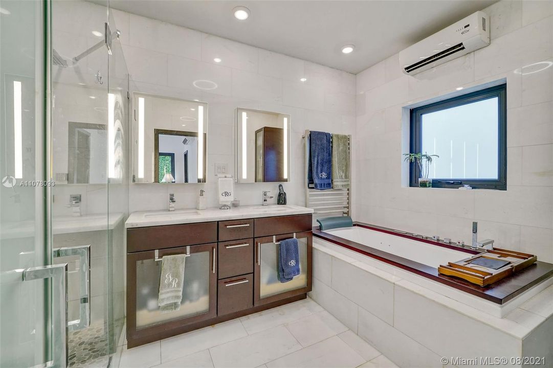 Primary bathroom with glass shower enclosure, soaking tub, and private room for toilet.