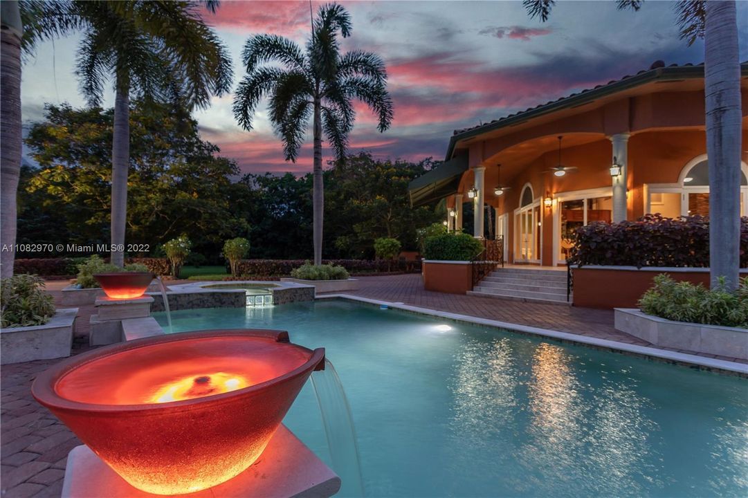 Dramatic lighted planter fountains around pool