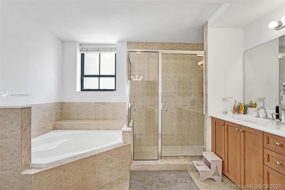Luxury primary bathroom boasts roman tub and separate shower