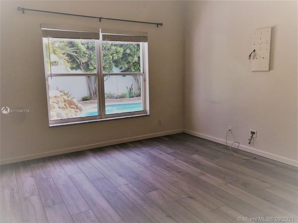 The large main bedroom enjoys a relaxing view of the pool and patio area.