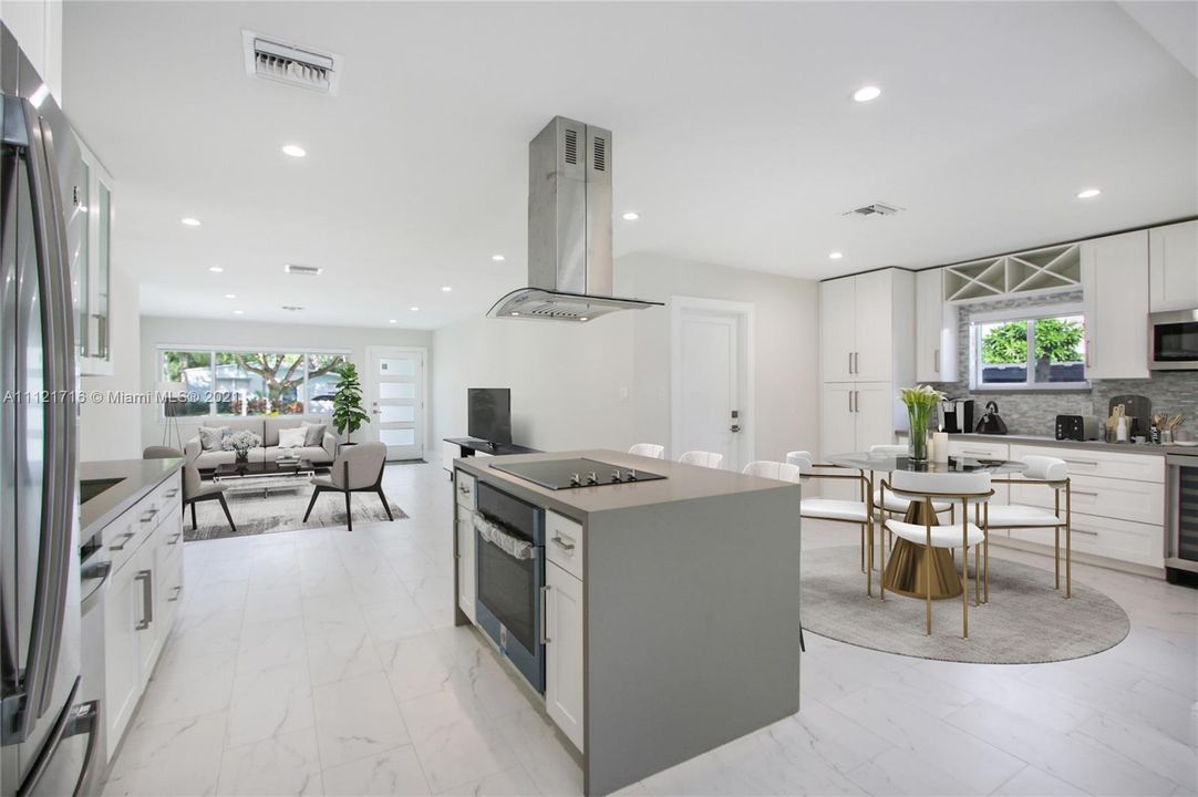 STAGGERING KITCHEN WITH UPGRADED APPLIANCES CUSTOME MADE WHITE CABINETRY HARMONIZE WITH GRAY QUARTZ COUNTER TOPS.