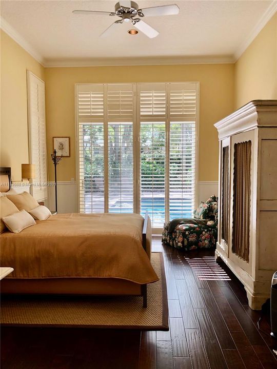 Master bedroom with plantation shutters and wood floor