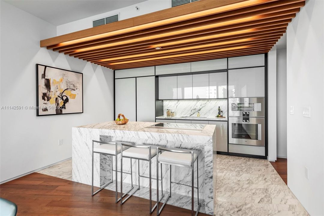Poliform kitchen with marble island in Calacatta gold, integrated wine cooler, & Gaggenau appliances.