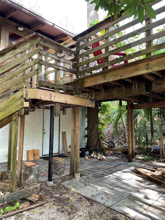 stairs to wood deck and front door upstairs, door to garage below deck.