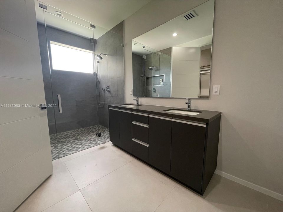 Master bathroom with glass enclosed shower and dual sink vanity.