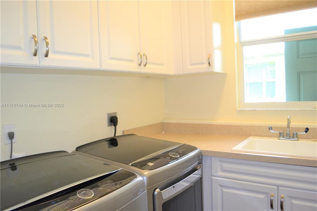 Laundry equipped with utility sink, cabinets and natural light.