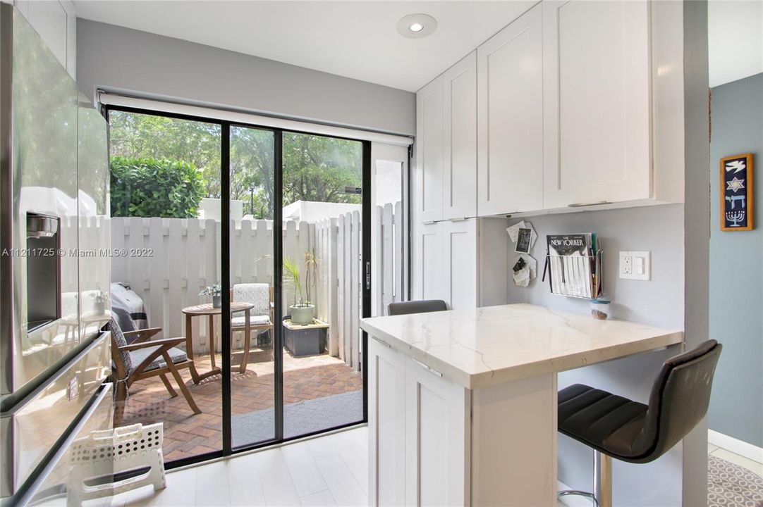 Sleek, modern white kitchen with its own eat-in counter. This home has large cabinets with plenty of storage.
