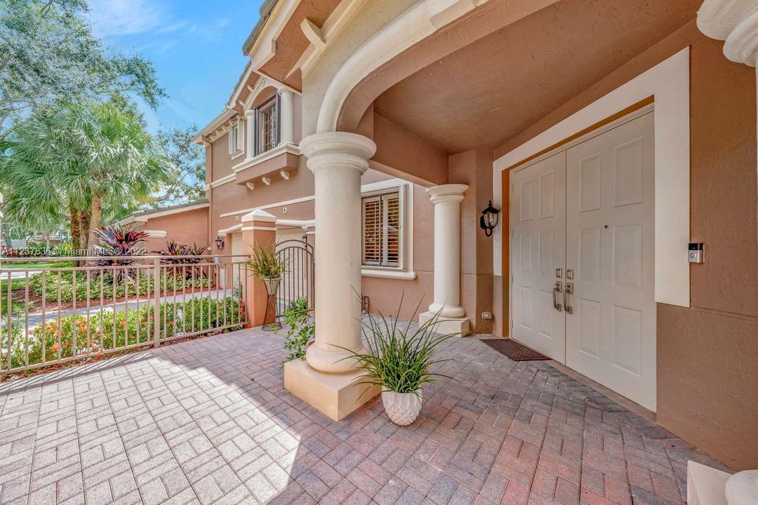 Double door entry with brick pavers and wraparound patio.  Long driveway with 2 car garage.