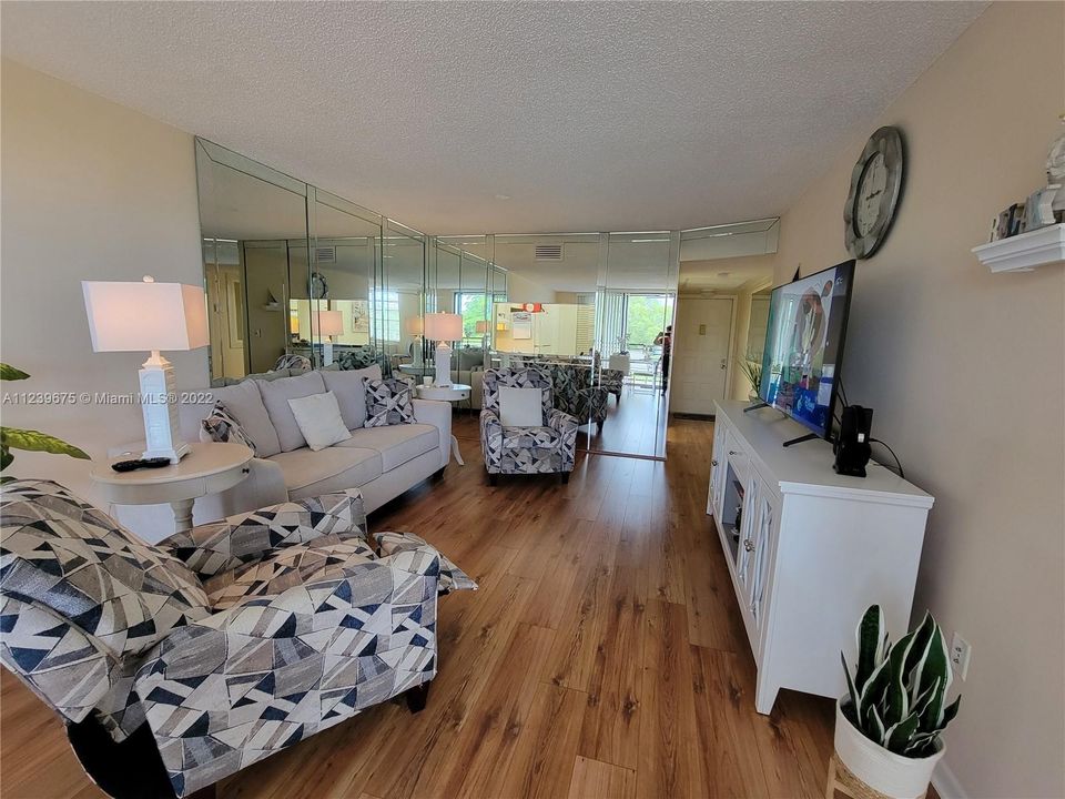 Expansive mirrored living room, beautifully furnished.