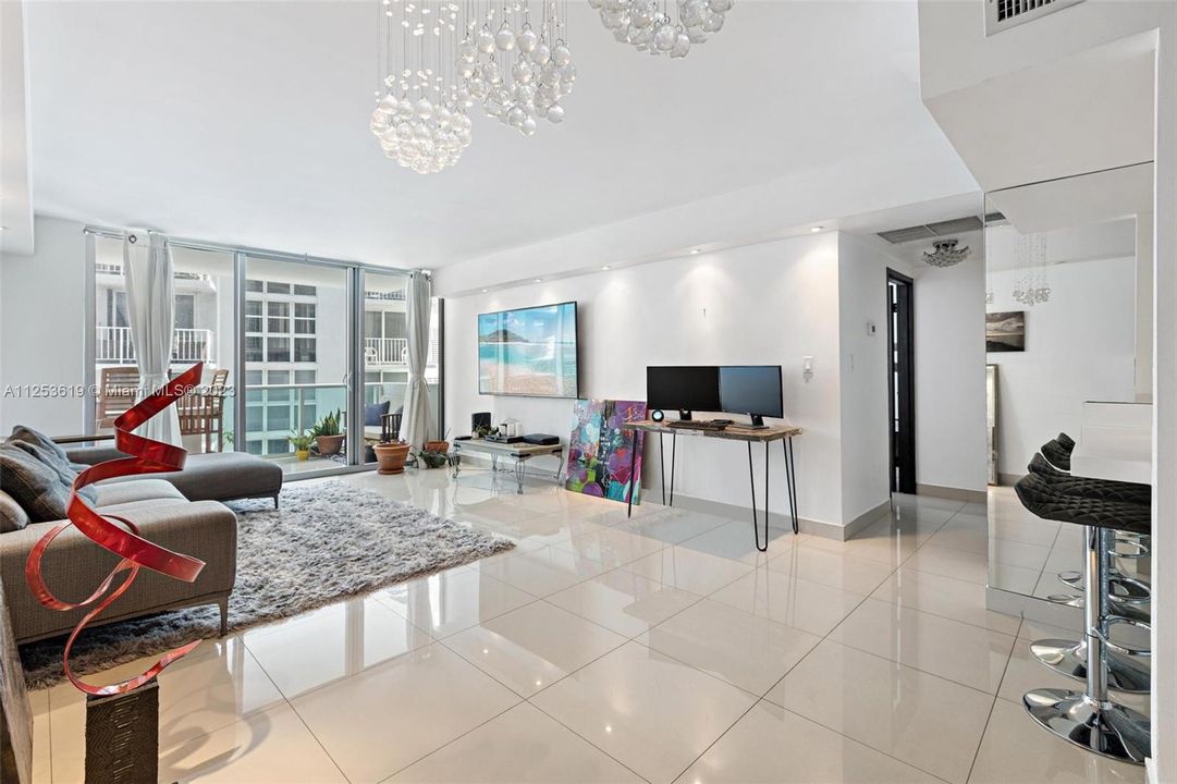 Spacious living room with white tile flooring and open kitchen.Unit #721, Mirador North Condo, Miami Beach, FL. For Sale.