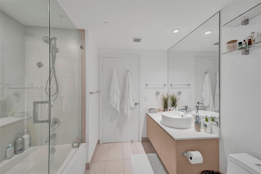 Bathroom has a combination tub/shower with glass doors.