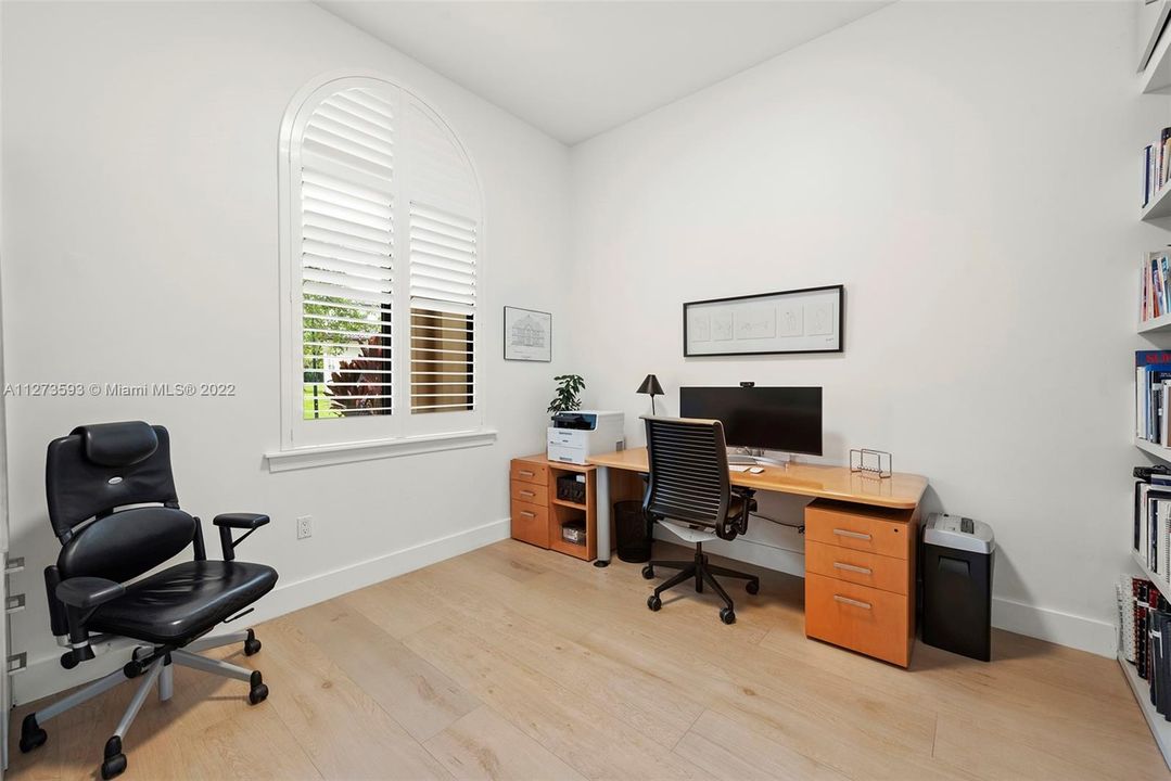 Office with plantation shutters and custom cabinetry.