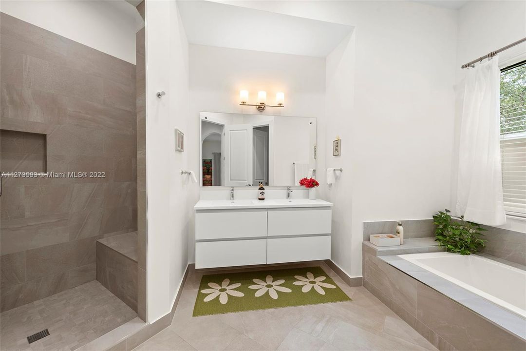Primary bathroom with double sinks, tub and bench in the shower.
