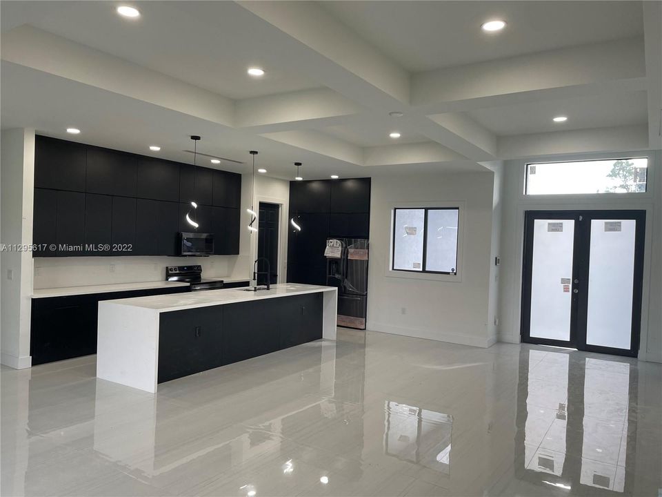 Luxury kitchen with white quartz and black custom cabinets. Porcelain 24 x 48 installed in all the house floor