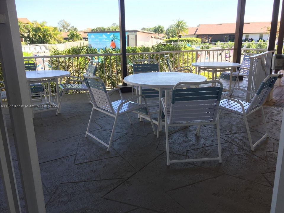 A SHADED AREA WITH TABLES OVER LOOKING POOL.