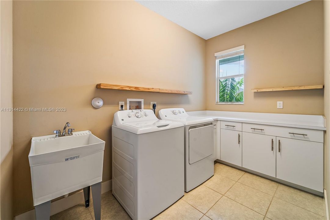 Upstairs laundry room with laundry tub & cabinetry