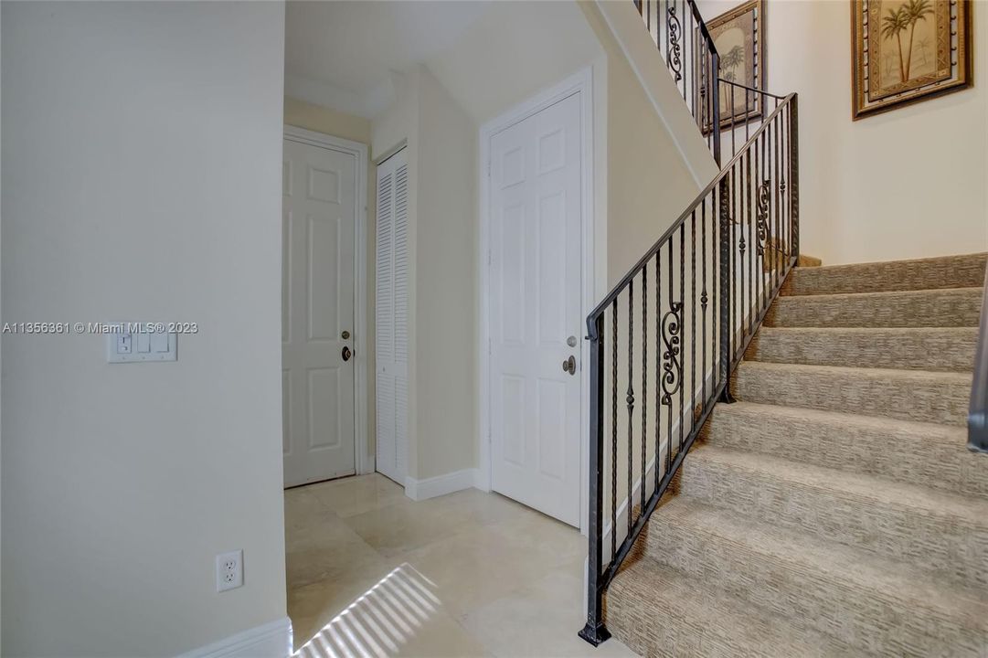 Foyer entry w/ powder room, coat closet and 2 car garage to the left, stairs w/ wrought iron railings and great room / kitchen to the right.