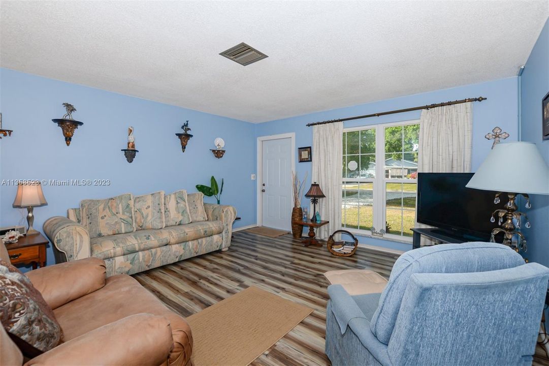 Roomy Living Room with large impact glass window and newer vinyl flooring