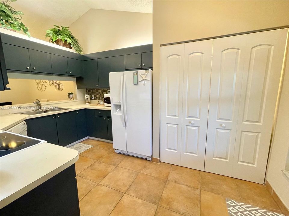 KITCHEN HAS DARK BLUE CABINETS WITH WINDOW PASS THOUGHT INTO THE DINING ROOM