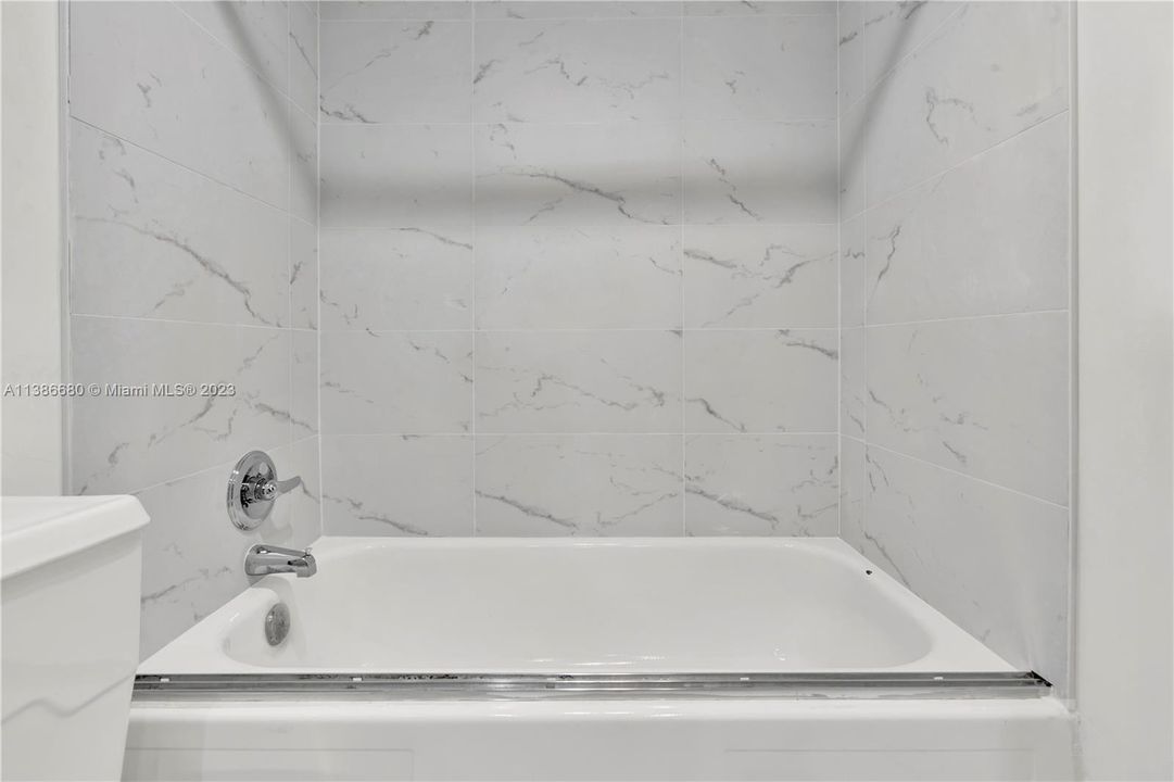 Bathtub within the 2nd Bathroom with Beautiful Marble Tile.