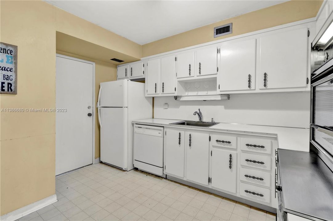 All-White Kitchen with Refrigerator and Dishwasher.