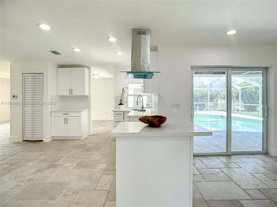 View from Family room to kitchen and pool area showing breakfast bar with quartz counter-tops.