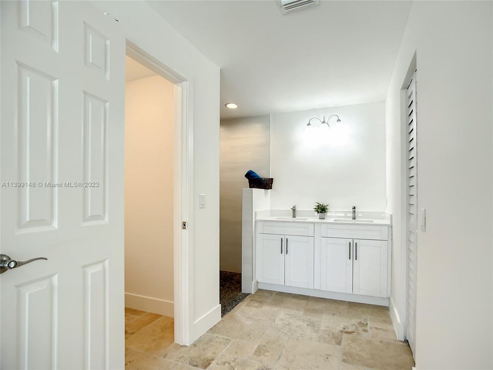 Additional primary bathroom view showing double sinks, private toilet area and walk-in closet.