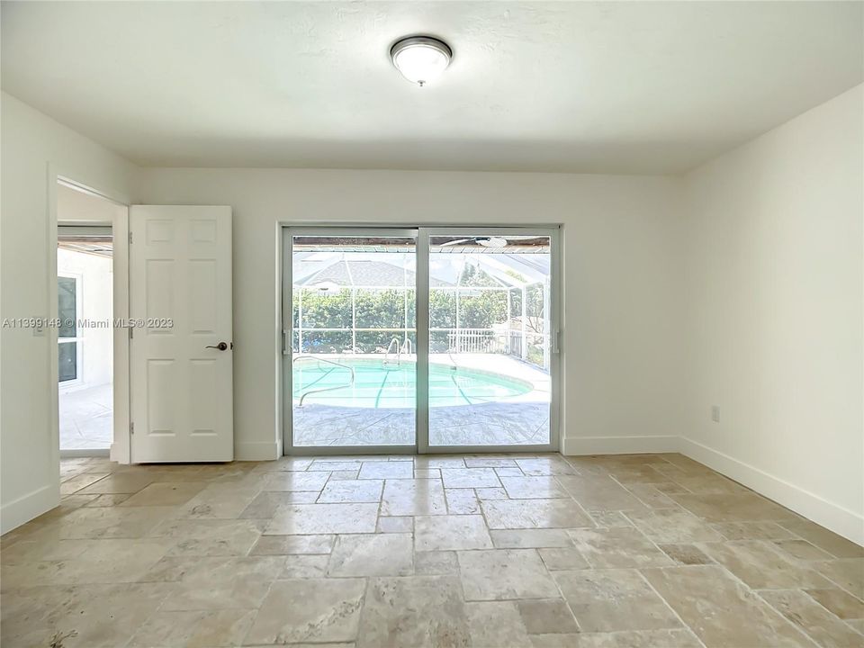 Primary bedroom has impact sliding doors with view to the pool area.