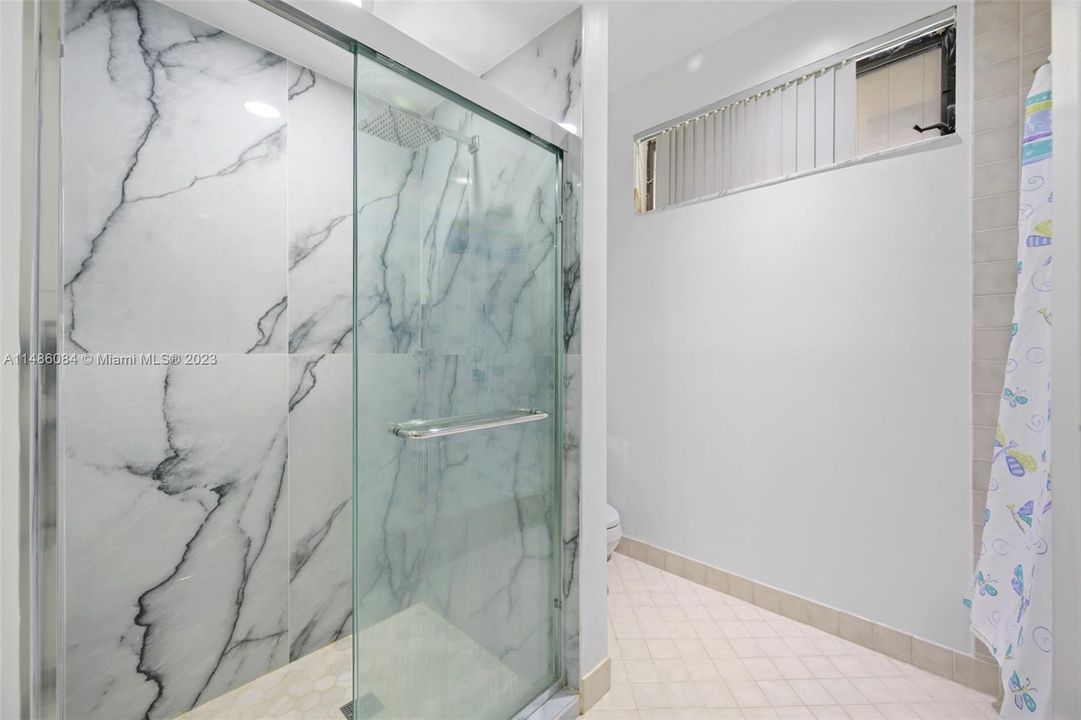 Renovated shower and a separate bathtub are located between two bedrooms