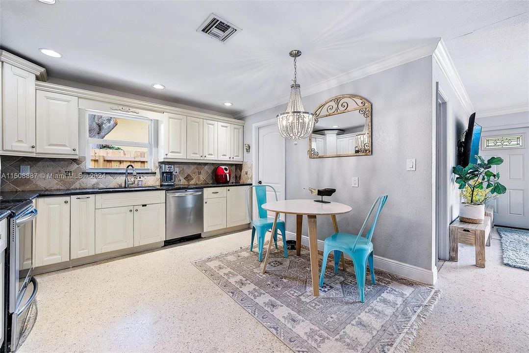 Kitchen with dining area. Granite countertops, stainless steel appliances and terrazzo flooring.