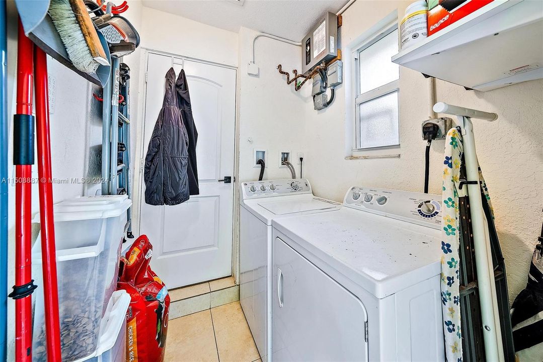 Utility room with washer. dryer, tankless water heater and storage access off kitchen. Also door that leads to outsuide.