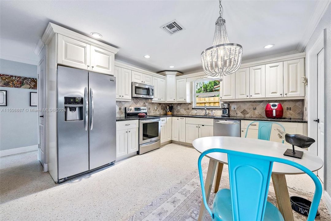 Kitchen with dining area. Granite countertops, stainless steel appliances and terrazzo flooring.