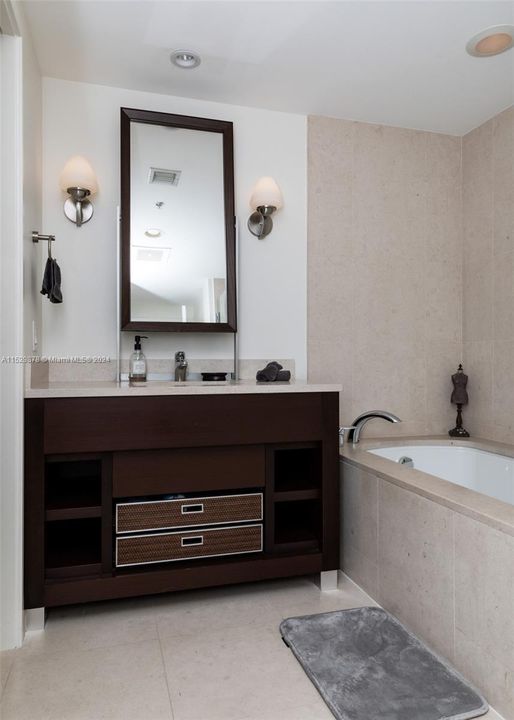 Vanity with single sink, tub, separate shower and private toilet with bidet set.