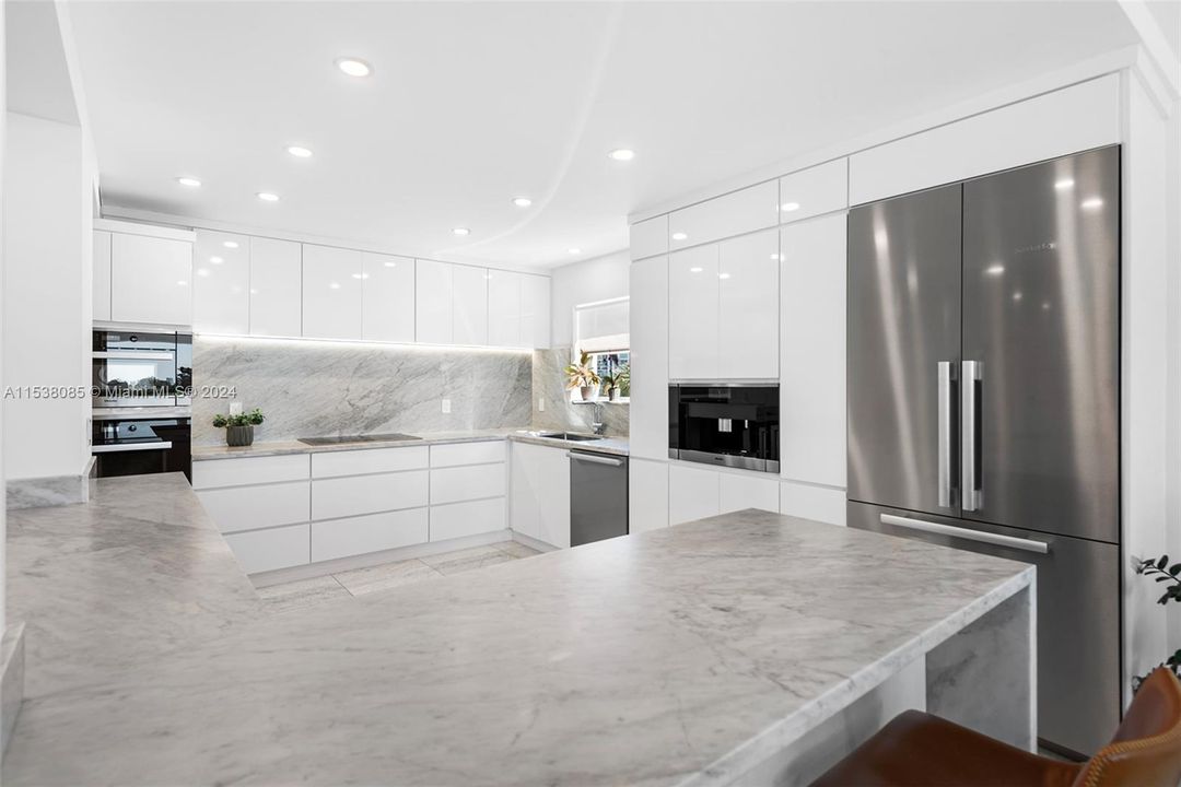 Remodeled open kitchen with Italian Carrara marble counters with waterfall edges and 30" inch marble backsplash