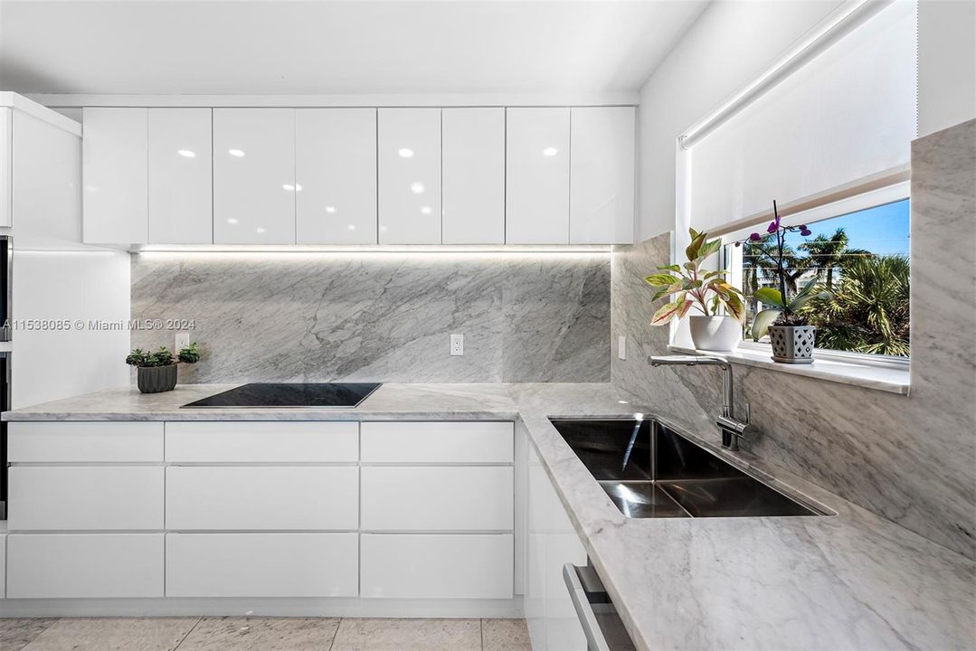 Custom, European style, white cabinetry and Franke sink system with accessories and Blanco faucet sprayer, all highlighted by Italian Carrara marble 30" inch backsplash